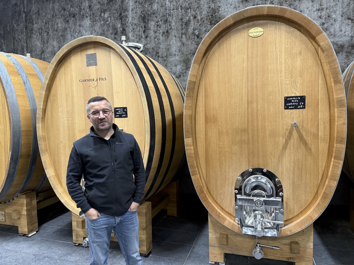 A winemaker standing beside large oak vessels in a cellar